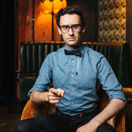 MC Hammersmith smiles in a professional headshot, wearing a dark jacket against a neutral background.