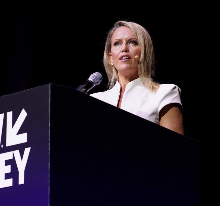 Jennifer Robinson speaks at a podium during SXSW Sydney 2023, wearing a white outfit against a dark background.